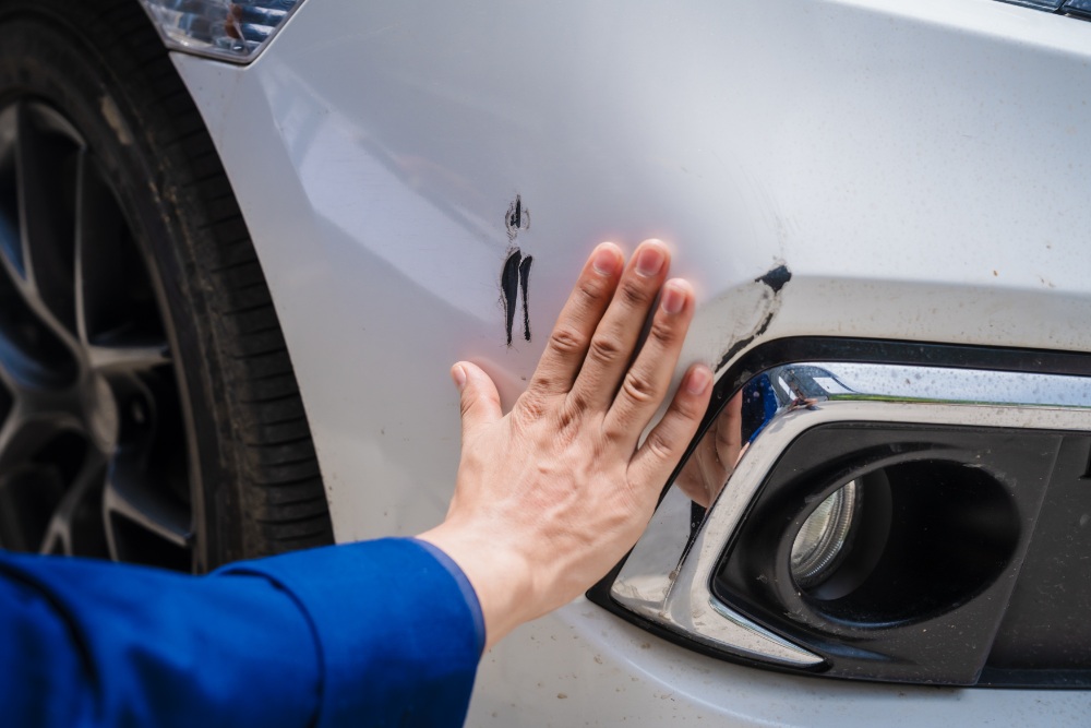 Hand berührt Autokarosserie-Schaden